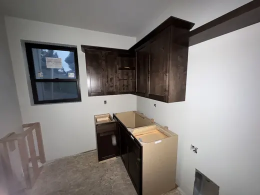 Dark wood wall cabinets, corner storage and appliance openings during installation, view 3.