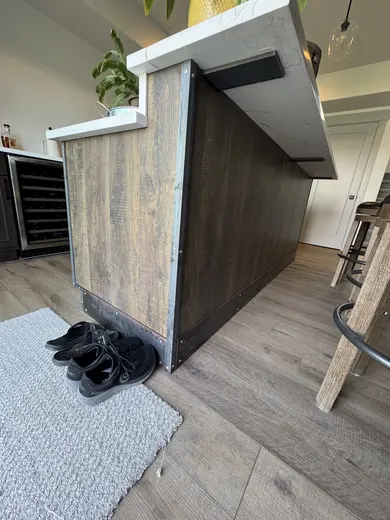 Wood island cladding with metal corner trim and visible fasteners, view 1.
