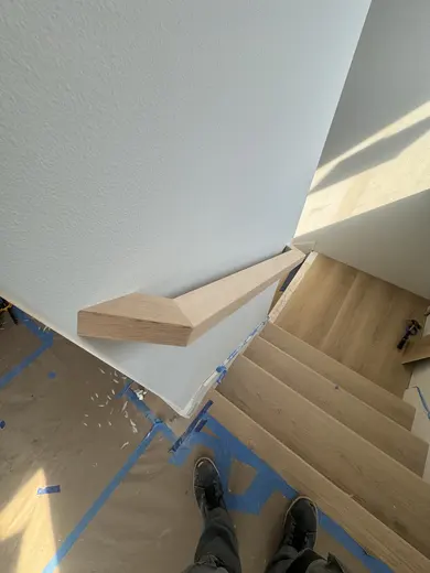 Stair-skirt fitting followed by wood handrails and black balusters on the same straight flight, view 8.