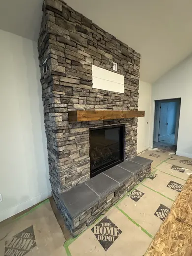 Wood ceiling beam and mantel installation in a vaulted room with a stone fireplace, view 5.