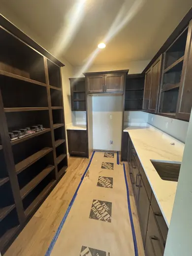 Dark wood kitchen and pantry cabinetry, sliding pantry doors, a green entry bench and adjacent stair-skirt details, view 14.