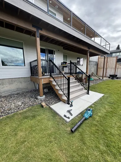 Pale decking, glass panels and black metal stair railings around the same outdoor space, view 1.
