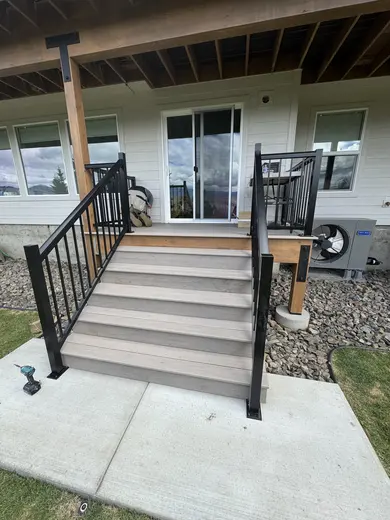 Pale decking, glass panels and black metal stair railings around the same outdoor space, view 2.