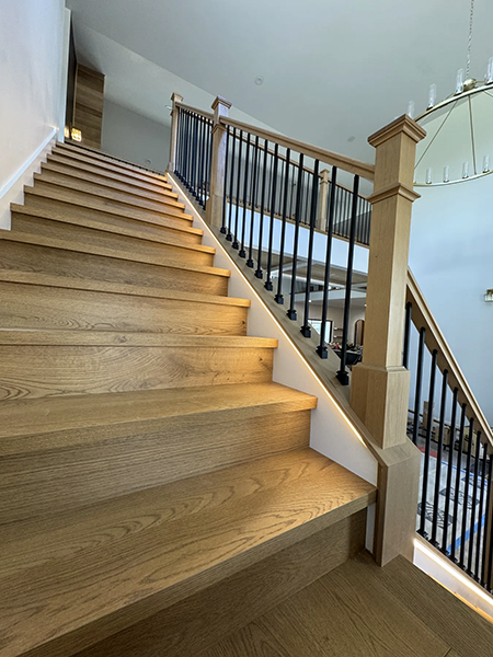 Wood staircase with step lighting and black balusters