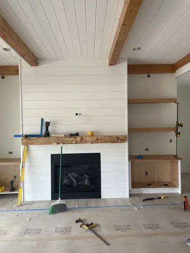 White plank ceilings, exposed wood beams, white cabinetry and a shiplap fireplace, view 3.
