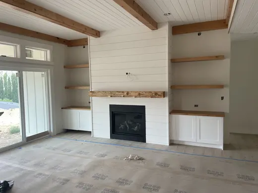 White plank ceilings, exposed wood beams, white cabinetry and a shiplap fireplace, view 5.
