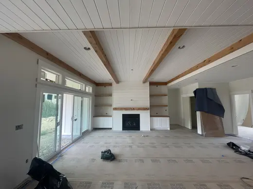 White plank ceilings, exposed wood beams, white cabinetry and a shiplap fireplace, view 6.