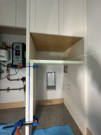 White cabinetry fitted around utility equipment and appliance openings, view 2.