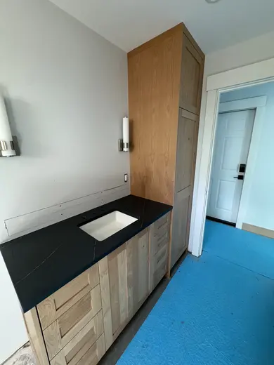Natural wood vanity and tall cabinet with a dark countertop, view 1.