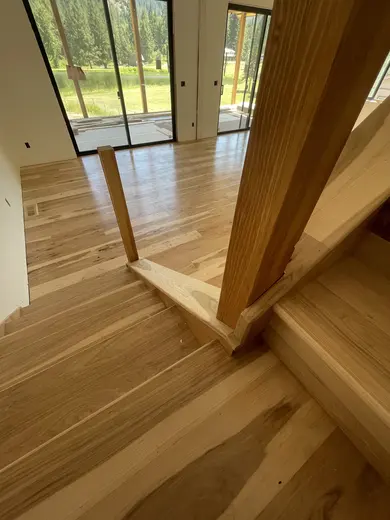 Wood stair treads and risers during installation; railing work remains, view 2.