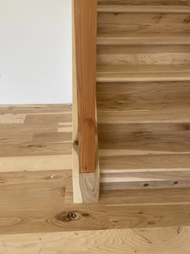 Wood stair treads and risers during installation; railing work remains, view 3.
