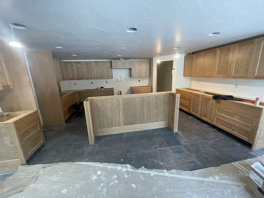 Wood railings with black balusters around a loft and the kitchen visible below, view 1.