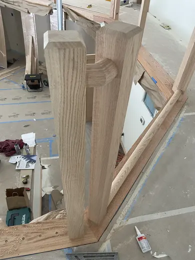 Wood railings with black balusters around a loft and the kitchen visible below, view 4.
