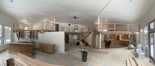 Wood railings with black balusters around a loft and the kitchen visible below, view 6.