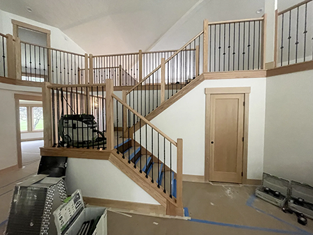 Wood railings with black balusters around a loft and the kitchen visible below, view 10.