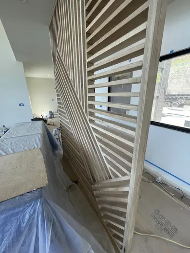 Intersecting wood slats beside the staircase, with wider installation views, view 2.