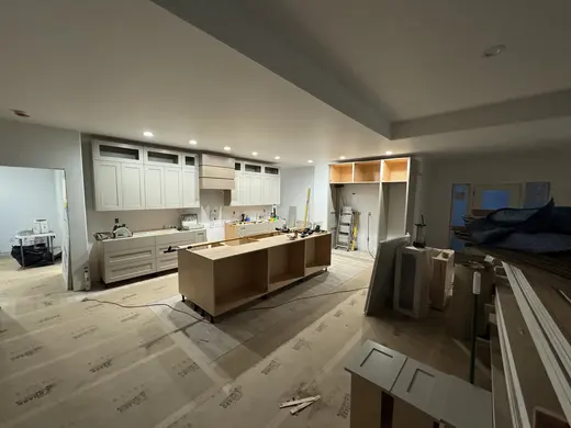 Gray cabinetry, refrigerator surround, bottle storage and a wood hood, view 1.