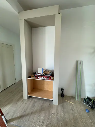 Fluted fireplace wall with side cabinets and shelves at successive installation stages, view 2.