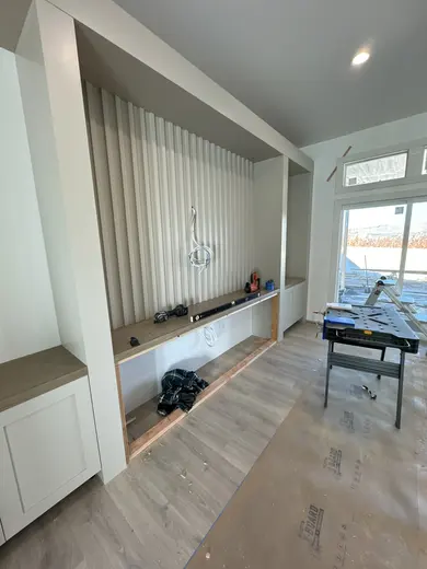Fluted fireplace wall with side cabinets and shelves at successive installation stages, view 3.