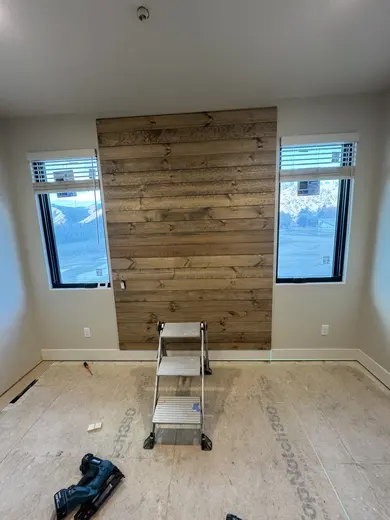 A wood plank feature wall between two windows, view 1.