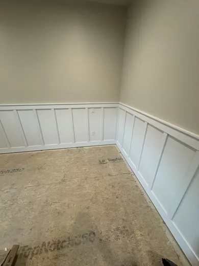 White lower-wall panel trim around a window and room corners, view 2.